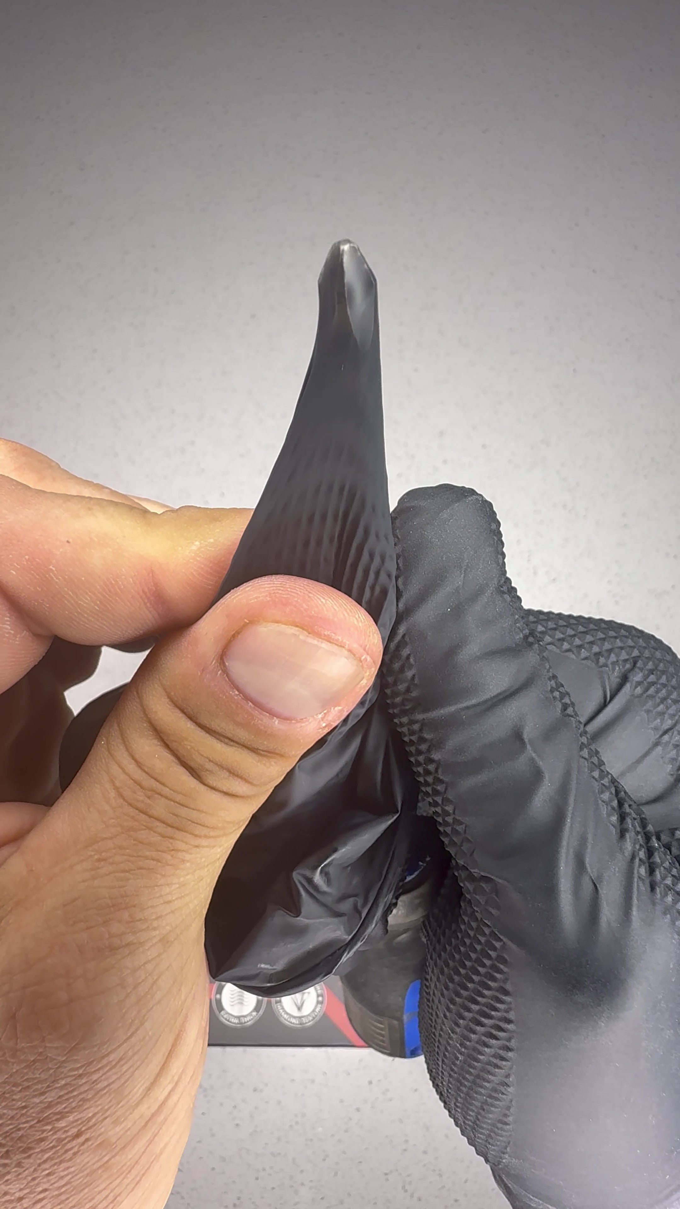 OGE 4X4 7 mil nitrile glove held against a screwdriver tip. Our own bench demonstration, not a rated puncture test. EN 388 mechanical protection is not claimed.